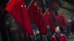 Una mujer pasa junto a una bandera&nbsp;china&nbsp;colgada en el barrio de Hutong durante la tercera jornada del el XIX Congreso del Partido Comunista de&nbsp;China&nbsp;(PCCh) en Pekín (China)el pasado 20 de octubre de 2017.&nbsp;