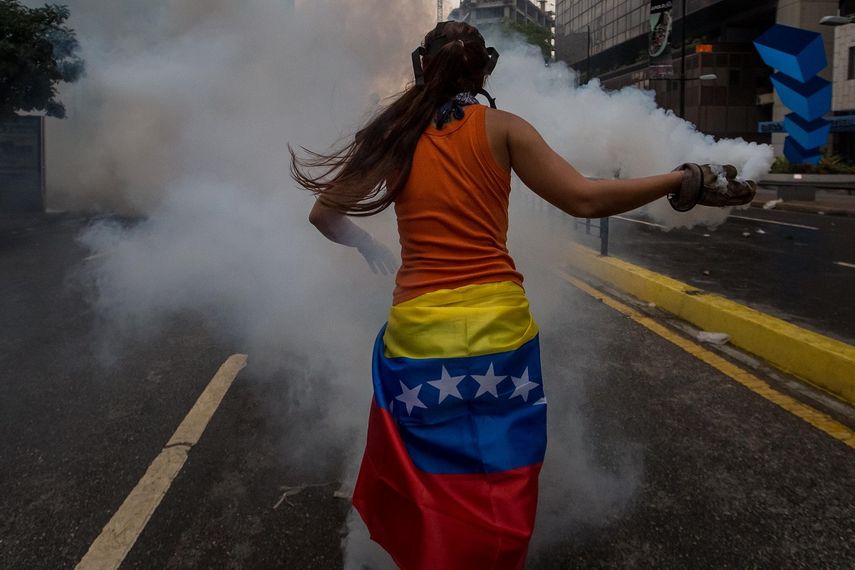Una joven mujer regresa una bomba lacrimógena a los agentes de la Guardia Nacional Bolivariana el pasado 20 de abril