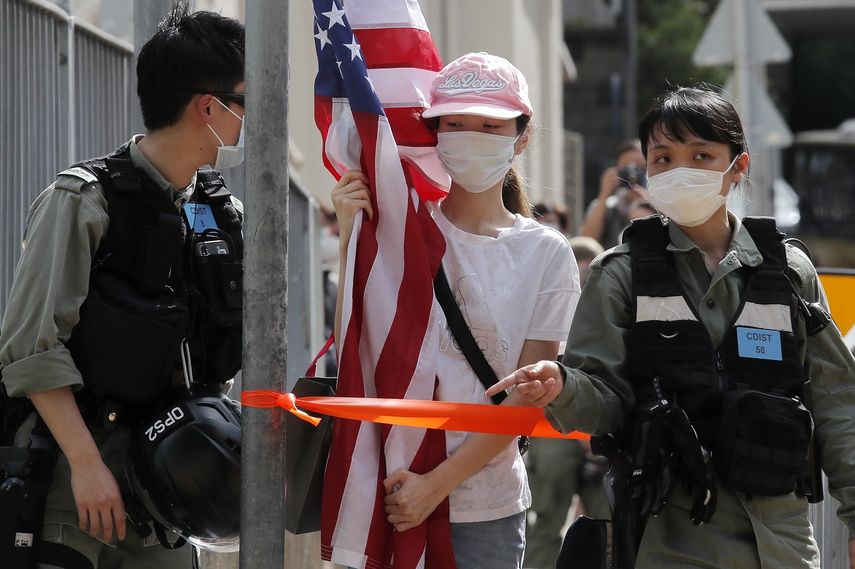 Polic&iacute;as antimotines dan el alto a una manifestante con una bandera estadounidense durante una protesta ante el consulado estadounidense en Hong Kong, el s&aacute;bado 4 de julio de 2020 por el D&iacute;a de la Independencia de Estados Unidos.