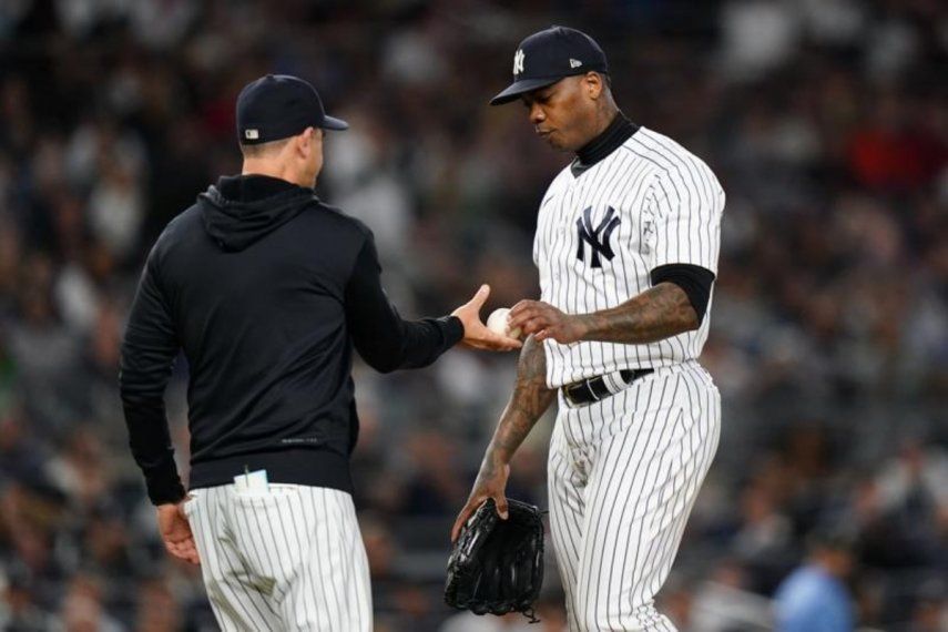 El relevista de los Yanquis de Nueva York, Aroldis Chapman, le entrega la pelota al mánager Aaron Boone durante un encuentro ante los Medias Rojas de Boston, el 22 de septiembre de 2022.