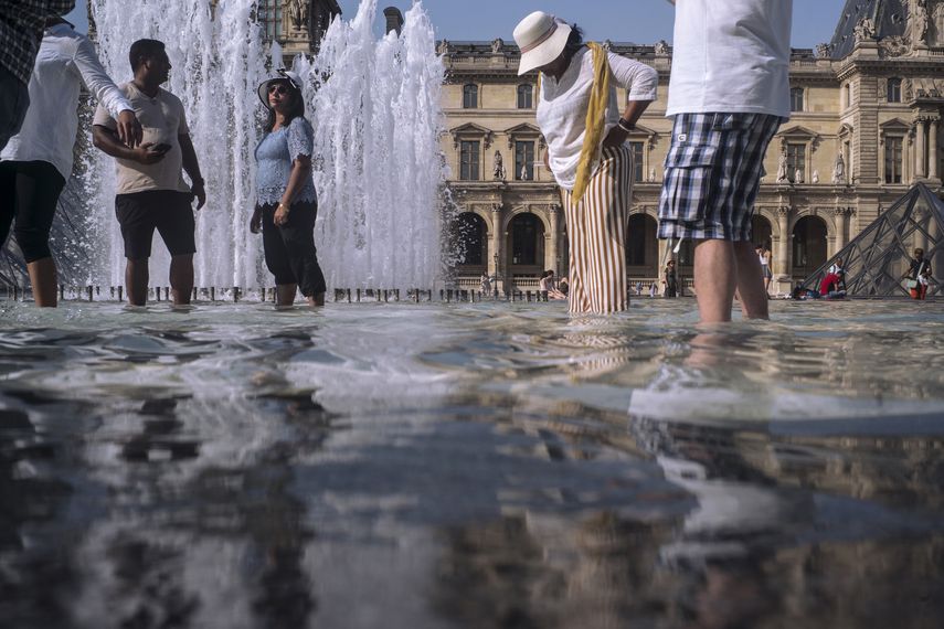 Gente refrescándose en las fuentes junto al Museo del Louvre en París, Francia, el miércoles 24 de julio de 2019.&nbsp;