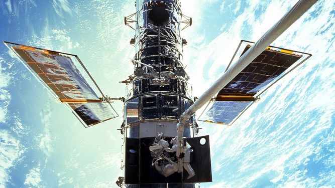 En esta imagen provista por NASA/JSC, los astronautas Steven L. Smith y John M. Grunsfeld realizan trabajos de mantenimiento del Telescopio Espacial Hubble en diciembre de 1999. El Hubble estará funcionando de nuevo pronto, luego de una difícil reparación remota por la NASA, se anunció el 16 de julio del 2021.
