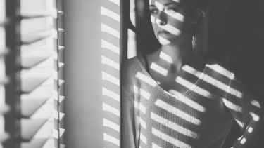 &nbsp;Mujer con deprensi&oacute;n frente a la ventana en su casa a causa del confinamiento provocado por el COVID-19