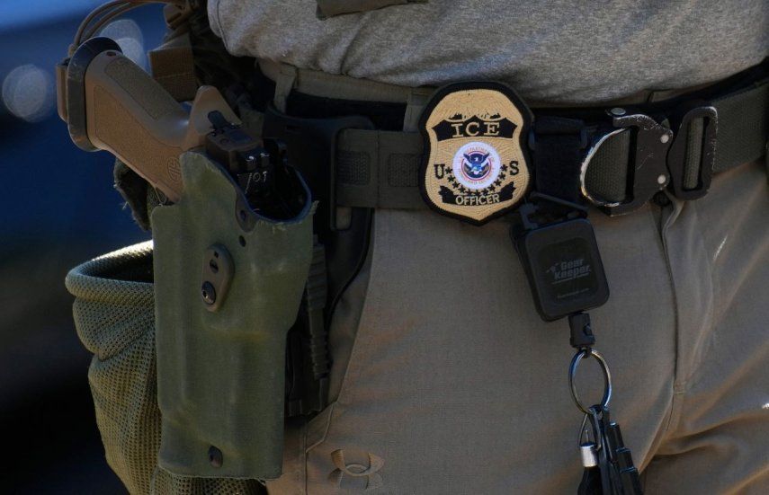 Se ve la placa y el arma de un oficial de Inmigración y Control de Aduanas (ICE) mientras ICE realiza un control de vehículos en Georgia Ave.