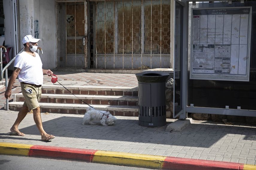Un hombre pasea con un perro junto a una papelera parlante instalada junto a una parada de autobús, en Jerusalén, el 14 de octubre de 2021.&nbsp;