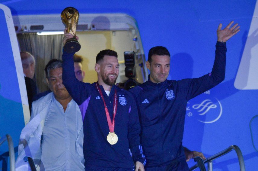El futbolista argentino Lionel Messi sostiene el trofeo del Mundial de la FIFA a la salida de un avión junto al técnico Lionel Scaloni, en Buenos Aires, Argentina, el martes 20 de diciembre 2022.&nbsp;