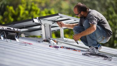 Un empleado instala paneles solares en el techo de una vivienda.