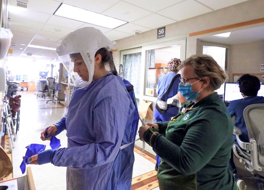 En esta fotografía del 5 de noviembre de 2020, Deb Dalsing, enfermera de la unidad de COVID-19 del hospital UW Health, ayuda a la enfermera Ainsley Billesbach con su equipo de protección, en Madison, Wisconsin.&nbsp;