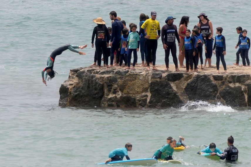 Jóvenes hacen clavados desde un muelle en la playa Carcavelos, afueras de Lisboa, martes 12 de julio de 2022. Una ola de calor en la península ibérica provoca temor de incendios forestales.