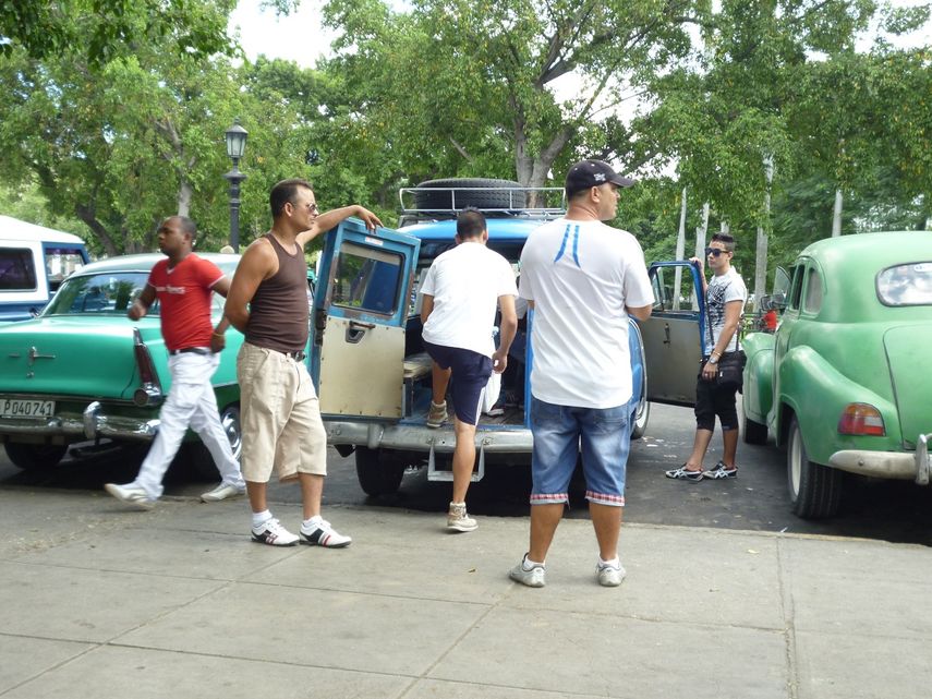 Vista de un grupo de boteros junto a sus autos en un parque de La Habana.
