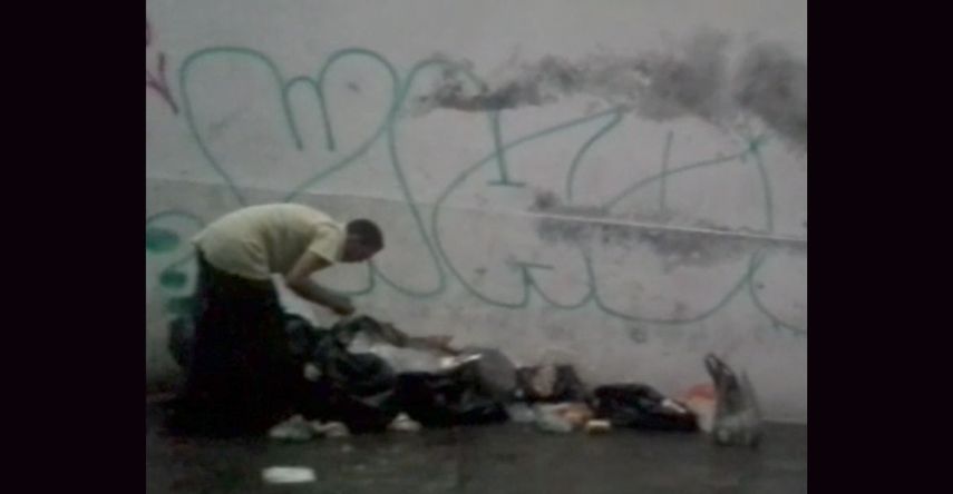 Un hombre abre las bolsas de basura para recoger comida. La escena se repite por toda la ciudad.