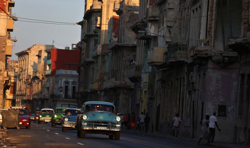 Varios autos de mediados del pasado siglo circulan por una calle de La Habana, Cuba.