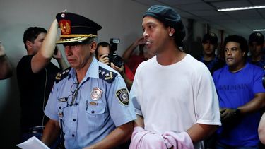 &nbsp; El ex astro brasile&ntilde;o de f&uacute;tbol Ronaldinho camina esposado a una audiencia judicial en Asunci&oacute;n, Paraguay, el s&aacute;bado, 27 de marzo del 2020.&nbsp; &nbsp;