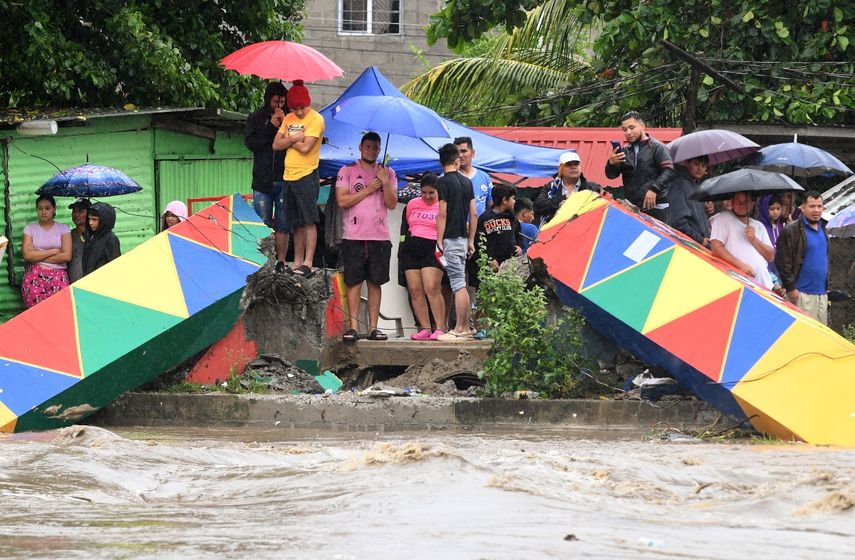 Personas de pie en el puente Saopin, destruido por el creciente caudal del río Cangrajal tras el paso de la tormenta tropical Sara en La Ceiba, Honduras, el 15 de noviembre de 2024.