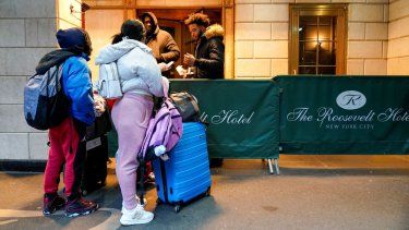 Una familia de migrantes muestra su documentación a los guardias de seguridad en el Hotel Roosevelt, el martes 9 de enero de 2024, en la ciudad de Nueva York. 