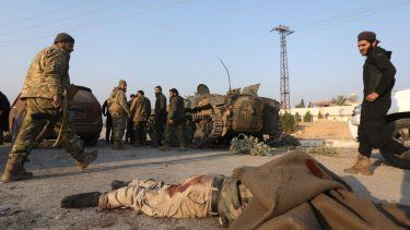 Insurgentes antigubernamentales cerca del cuerpo de un soldado sirio en una calle de Hama después de tomar el control de la ciudad central de Siria, el 6 de diciembre de 2024.