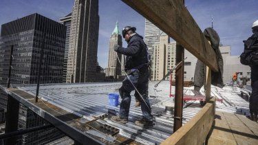 Trabajadores de la construcción instalan el techo de un edificio.