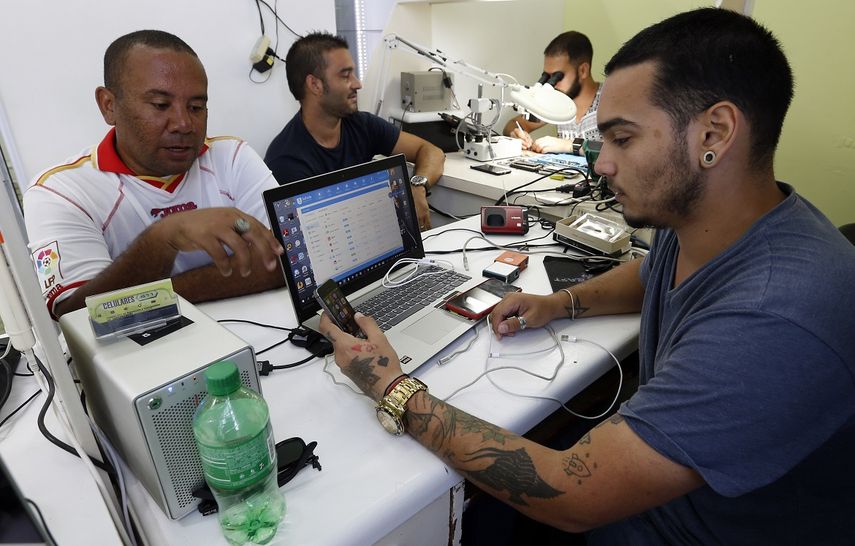 Dos personas acuden a un negocio privado de reparación de teléfonos celulares en La Habana, Cuba. 