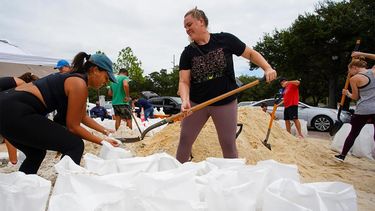 Vecinos de Tampa llenan sacos de arena.
