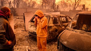 Dos personas entre cenizas y escombros que dejaron las llamas de uno de los incendios en Altadena, en el condado Los Angeles, California.