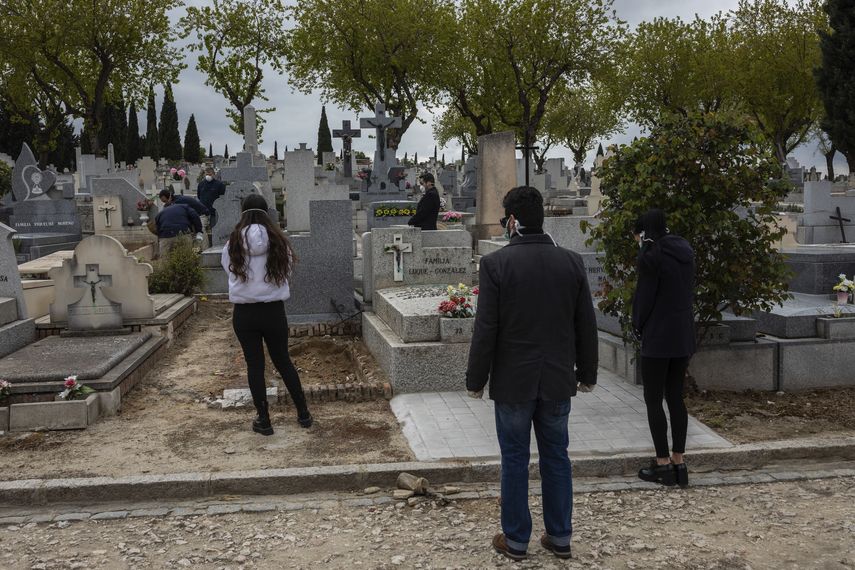 Familiares, con mascarillas respetan el protocolo de distancia social durante un entierro en un cementerio de Madrid, durante el brote del coronavirus, el 27 de marzo de 2020.&nbsp;