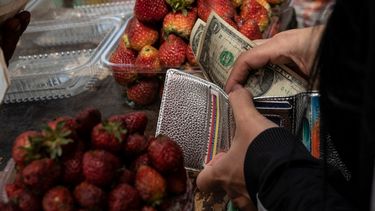 Una mujer guarda su cambio en billetes de un dólar después de comprar fruta en un puesto del mercado municipal de Quinta Crespo en Caracas.