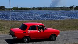Un automóvil de la era soviética pasa junto a un parque fotovoltaico en Cienfuegos, Cuba, el 20 de marzo de 2025. No muy lejos de las ruinas de una central nuclear inacabada en la provincia cubana de Cienfuegos, cientos de trabajadores instalan apresuradamente 44.000 paneles solares mientras la isla busca reducir una vez más su dependencia del petróleo para escapar de una crisis energética.