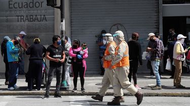 Trabajadores con trajes de protección para prevenir el nuevo coronavirus caminan junto a peatones en Quito, Ecuador, el miércoles 10 de junio de 2020.&nbsp;