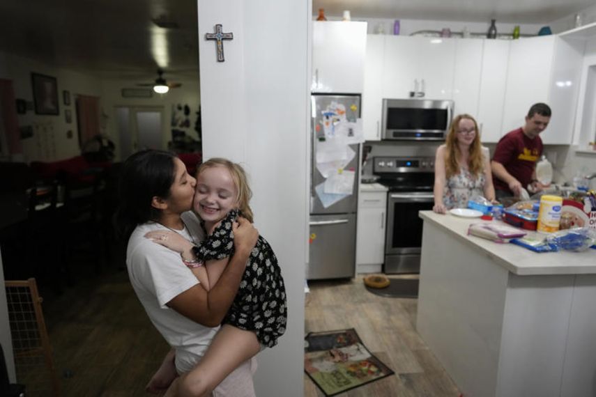 Sol, argentina de 14 años, besa a Maddie Hazelton mientras juegan en la cocina de los padres que acogieron a Sol, Andy y Caroline Hazelton en Homestead, Florida, 18 de diciembre de 2023
