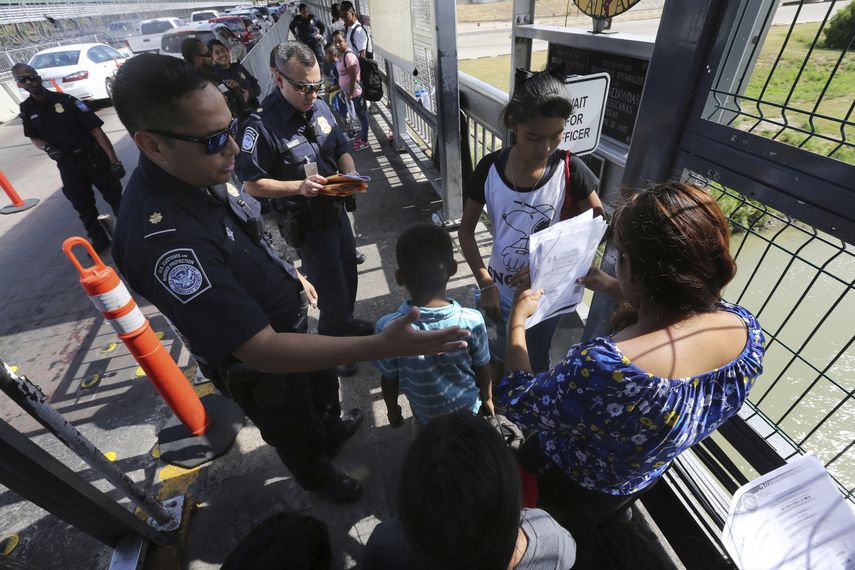 Un agente fronterizo estadounidense verificando los documentos de migrantes antes de ser llevados a solicitar asilo en Estados Unidos, en el Puente Internacional 1 en Nuevo Laredo, M&eacute;xico.&nbsp;