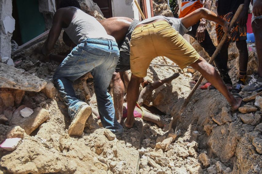 Un grupo de personas trabaja para recuperar un cuerpo enterrado por los escombros de una vivienda luego de un sismo en Los Cayos, Haití, el sábado 14 de agosto de 2021.