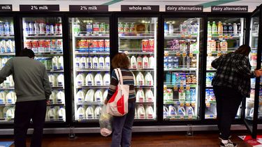 Clientes observan los precios en la sección de lácteos en un supermercado.