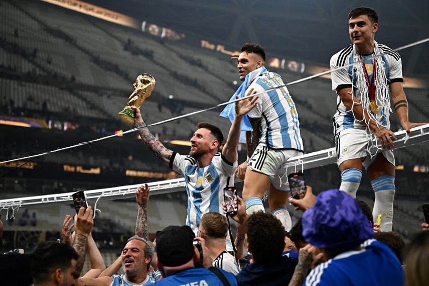 El capitán y delantero argentino #10 Lionel Messi sostiene el Trofeo de la Copa Mundial de la FIFA luego de la ceremonia de entrega de trofeos después de que Argentina ganó el partido de fútbol final de la Copa Mundial Qatar 2022. Artistas de todo el mundo celebraron el triunfo.