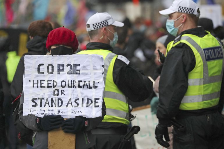 Una activista por el clima sostiene un cartel junto a policías cerca de la sede de la Conferencia de Naciones Unidas sobre Cambio Climático, o COP26, en Glasgow, Escocia, el 12 de noviembre de 2021. 