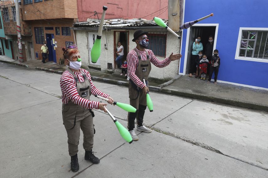 Los miembros de la compa&ntilde;&iacute;a Circo Encuentro realizan un acto de malabarismo para los residentes, mientras esperan que una caldera de sopa se cocine con alimentos donados en Bogot&aacute;, Colombia, el s&aacute;bado 4 de julio de 2020.&nbsp;