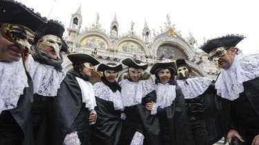 En esta foto del 11 de febrero de 2017, hombres usan mascaras, algunas de ellas de médicos de plagas, en la Plaza de San Marco en Venecia, Italia.