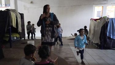 Una mujer hondureña que espera para entrar a Estados Unidos (centro), se peina mientras sus unos niños juegan cerca, en un albergue en Tijuana, México, el 17 de febrero de 2021.&nbsp; &nbsp;