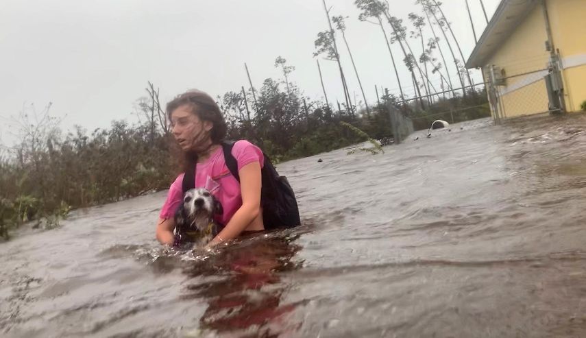 Julia Aylen se pasea por el agua hasta la cintura llevando a su perro mascota mientras es rescatada de su hogar inundado durante el huracán Dorian en Freeport, Bahamas, el martes 3 de septiembre de 2019. 