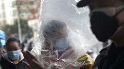 Un hombre cubre su rostro con una mascarilla y una bolsa de pl&aacute;stico, tras el brote de coronavirus en Wuhan, en la provincia central china de Hubei, el lunes 10 de febrero de 2020.