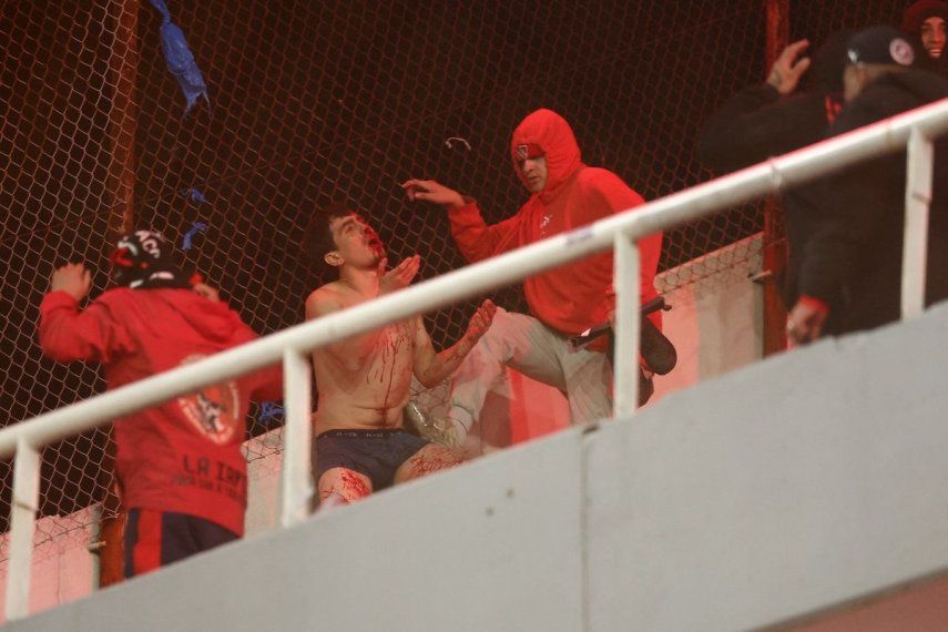 Un hincha de la Universidad de Chile sangra al ser golpeado por hinchas de Independiente durante la interrupción del partido de vuelta de los octavos de final de la Copa Sudamericana entre Independiente de Argentina y Universidad de Chile de Chile, en el estadio Libertadores de América en Avellaneda, provincia de Buenos Aires, Argentina, el 20 de agosto de 2025