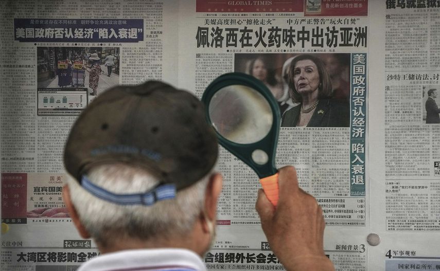 Un hombre lee la prensa con una lupa en Pekín.