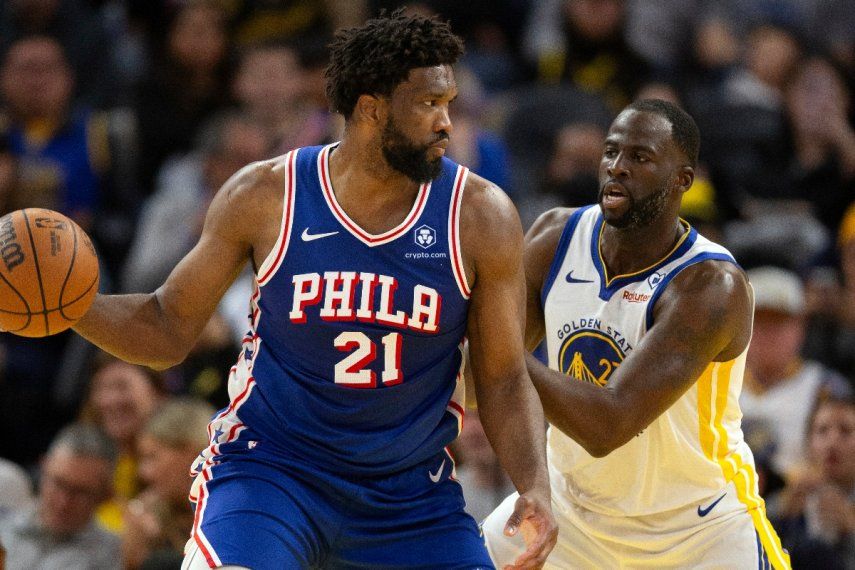 El pívot de los 76ers de Filadelfia Joel Embiid observa antes de pasar el balón mientras lo defiende el alero de los Warriors de Golden State Draymond Green en el encuentro del martes 30 de enero del 2024.&nbsp;