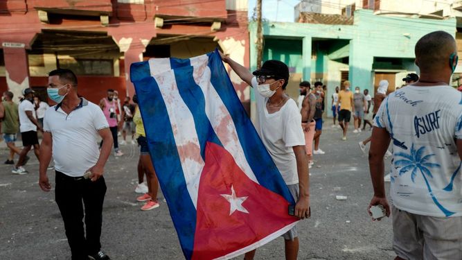 Un manifestante muestra la bandera cubana manchada de sangre durante el estallido social.
