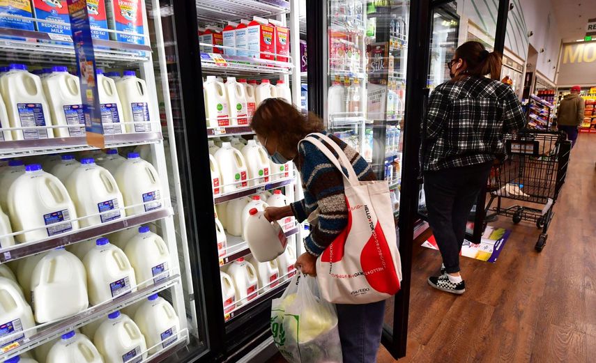 Una mujer toma un galón con leche en un supermercado.