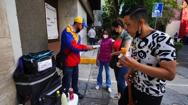 Venezolanos que viven en Ciudad de México le compran empanadas y otros productos de su tierra al vendedor callejero Nelson Banda frente a la embajada de Venezuela en la capital mexicana el 20 de abril del 2022.