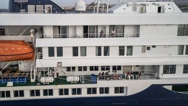 Esta vista aérea muestra a los pasajeros observando cómo personal sanitario, invisible para el público, ayuda a los pacientes a subir a un bote desde el crucero MV Hondius, mientras este se encontraba anclado frente al puerto de Praia, la capital de Cabo Verde, el 6 de mayo de 2026. &nbsp;