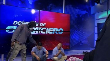 Imagen extraída del vídeo emitido por el canal TC Televisión en el que aparece un hombre encapuchado y armado al lado de dos trabajadores del medio en plena retransmisión en vivo, en Guayaquil, Ecuador, el martes 9 de enero de 2024. 