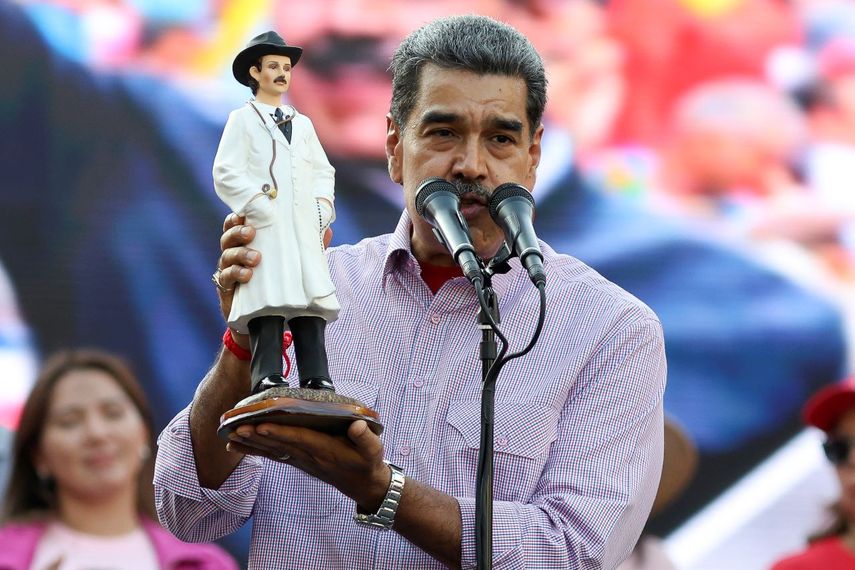El dictador de Venezuela, Nicolás Maduro, sostiene una imagen del médico venezolano José Gregorio Hernández durante un mitin político.