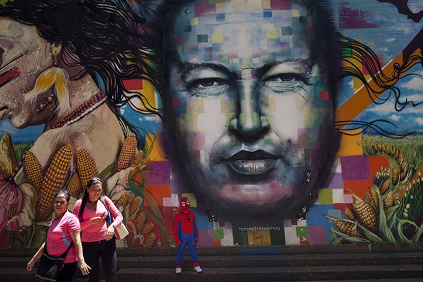Un niño vestido con un disfraz de hombre araña posa para una foto junto a un mural del fallecido presidente de Venezuela, Hugo Chávez, pintado en una pared del Museo de Bellas Artes de Caracas, Venezuela. (AP)