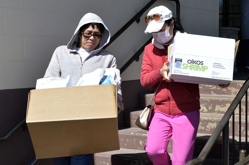 Dos mujeres salen de una pescader&iacute;a con cajas de mariscos.
